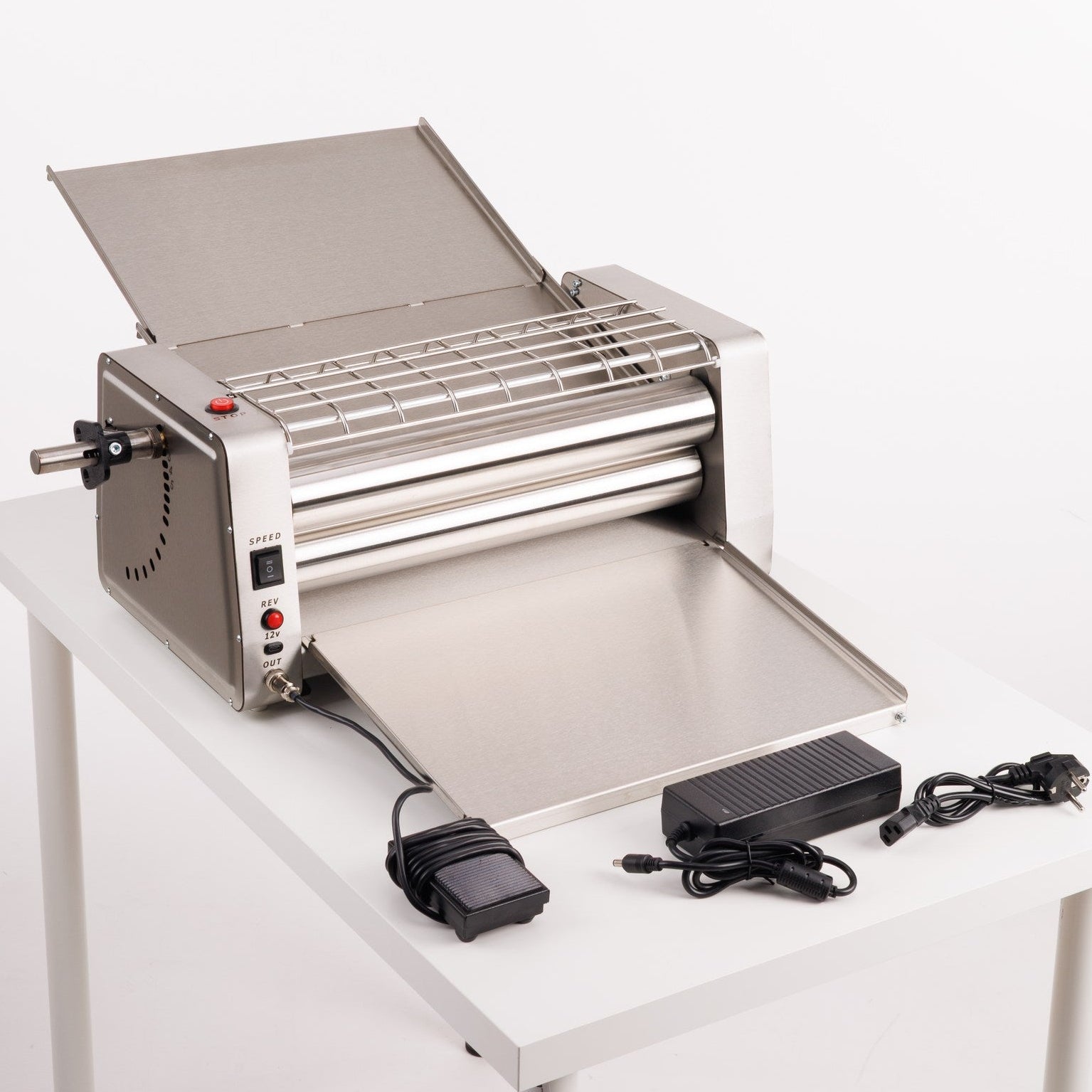 Stainless steel pasta machine on a white table with a white background