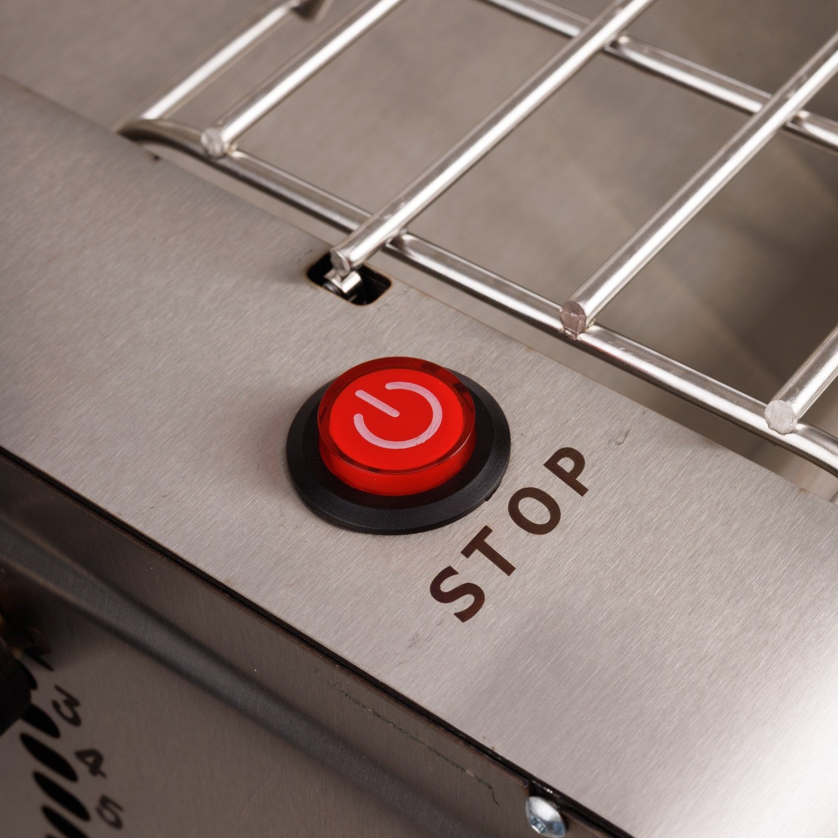Close-up of a metal grill with a red 'Stop' button